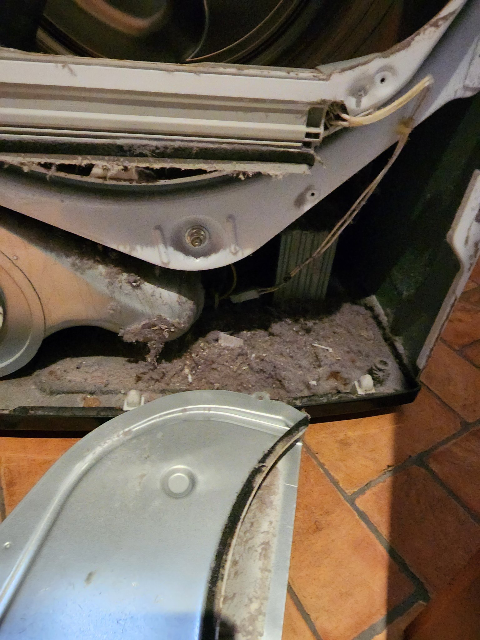 Inside a dryer opened up showing lint everywhere