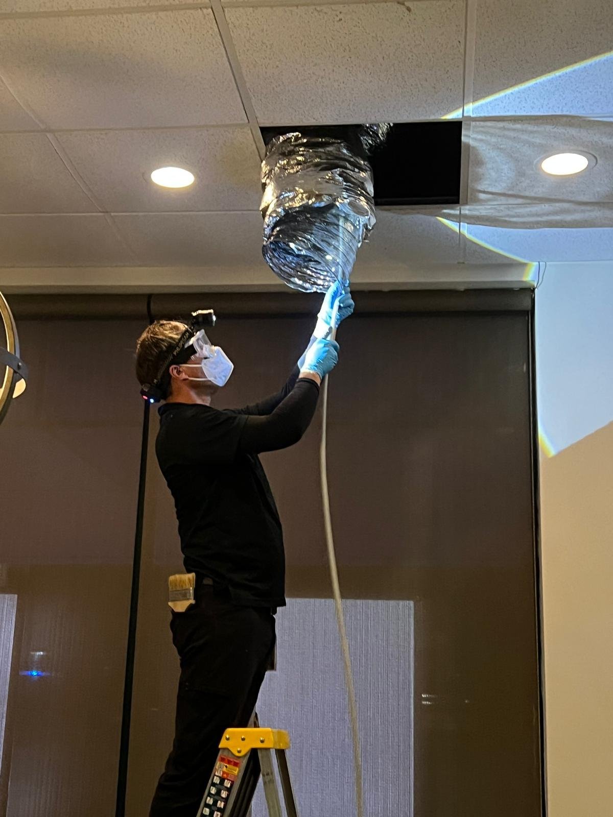 Technician Cleaning A Ceiling Flex Duct