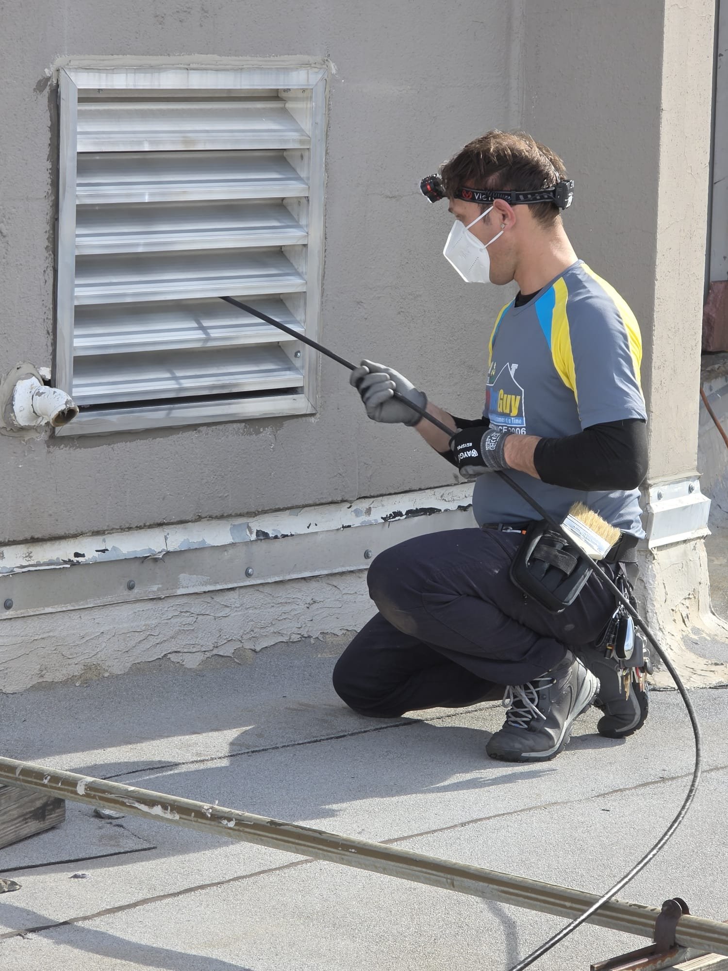 Technician Cleaning A Large Outdoor Wall Vent