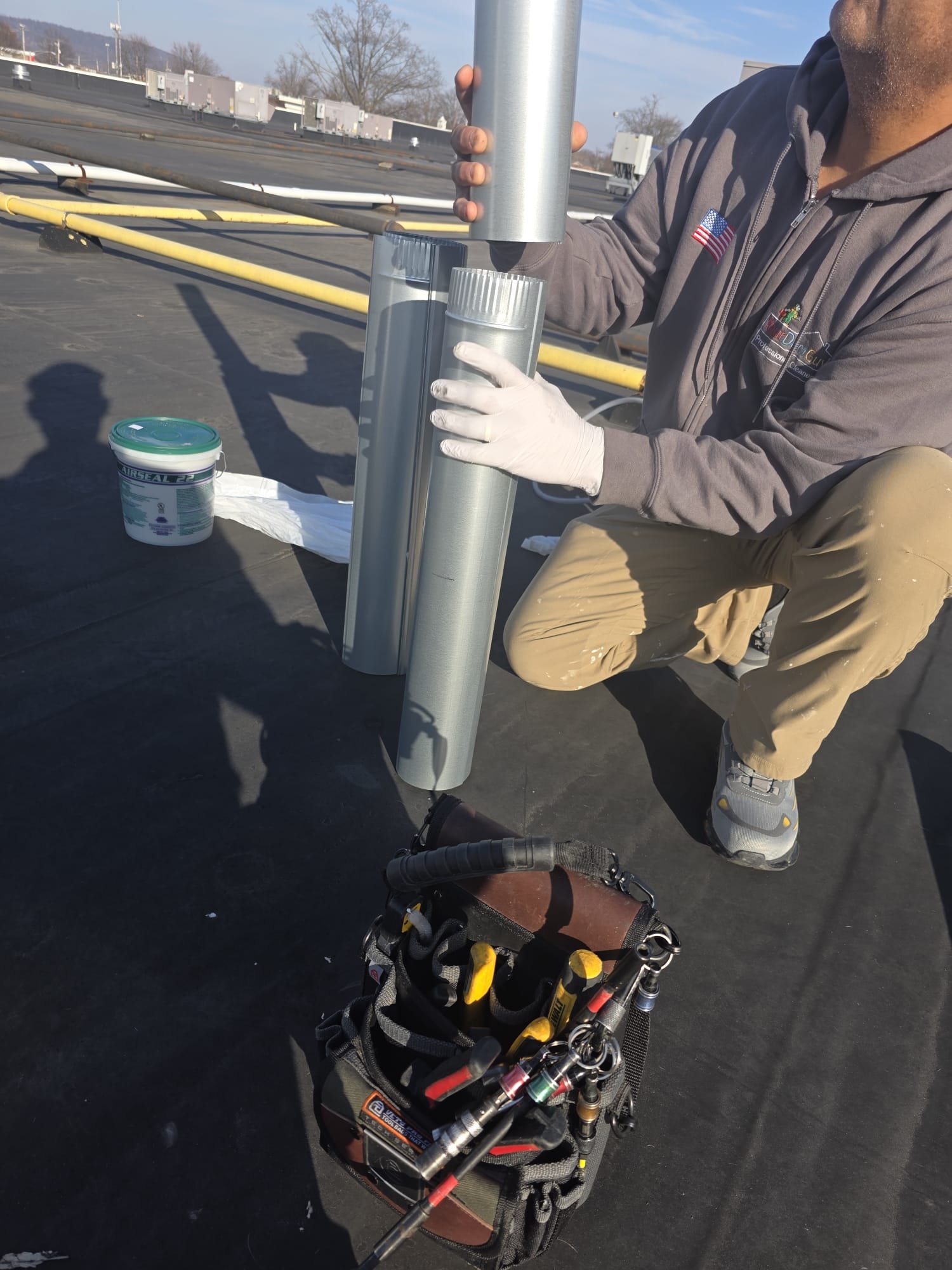 Technician assembling new metal duct pipe on a commercial rooftop