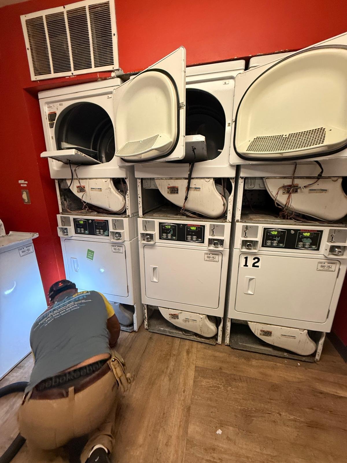 Technician Working Behind A Bank Of Commercial Dryers