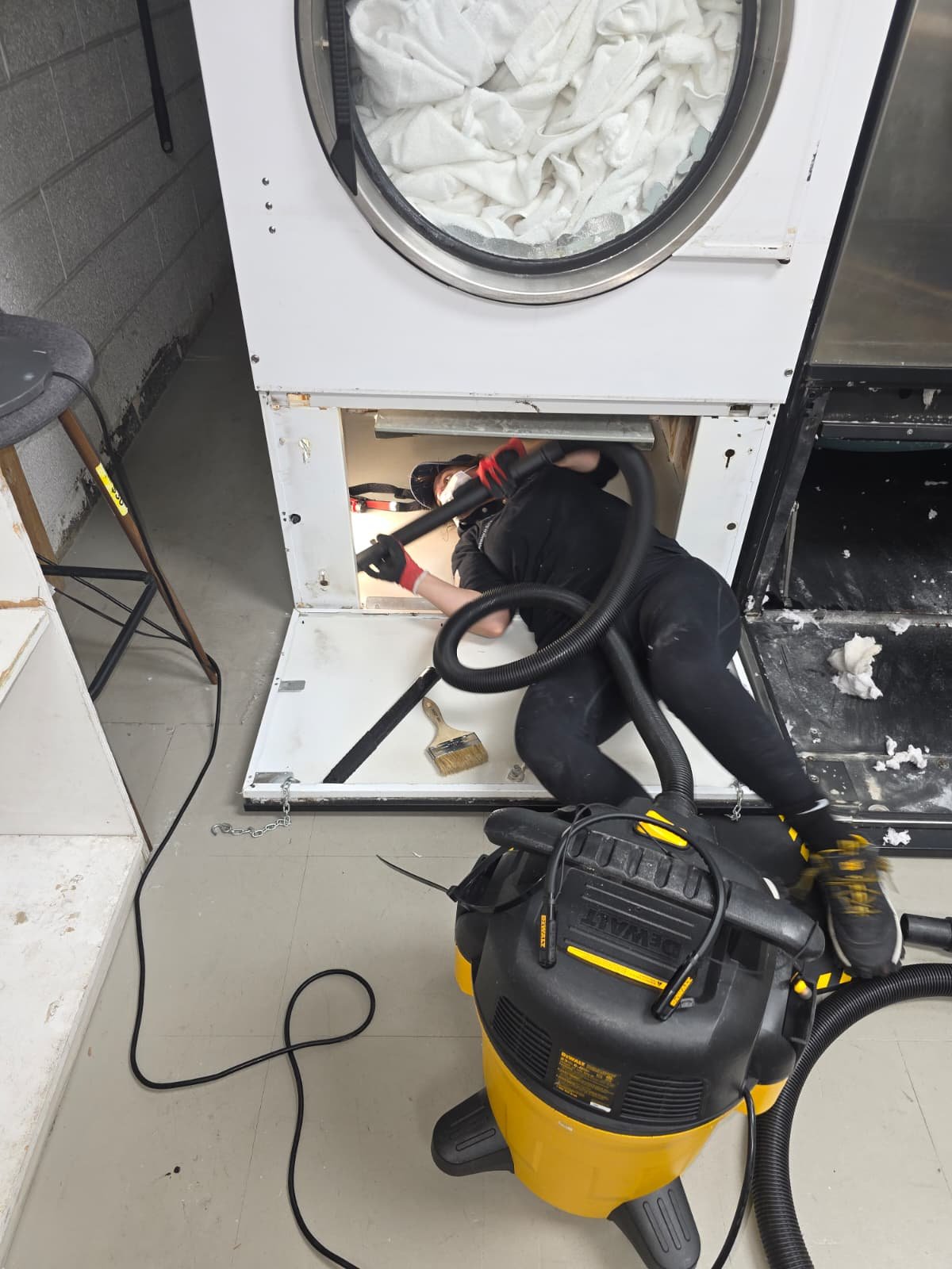 Technician Vacuuming Inside A Large Commercial Dryer