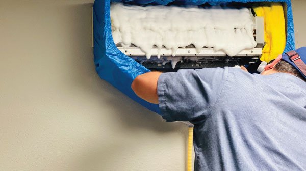 Technician foaming a mini-split coil during deep clean