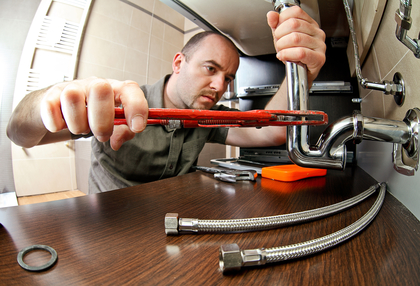 Plumber tightening pipes with a wrench